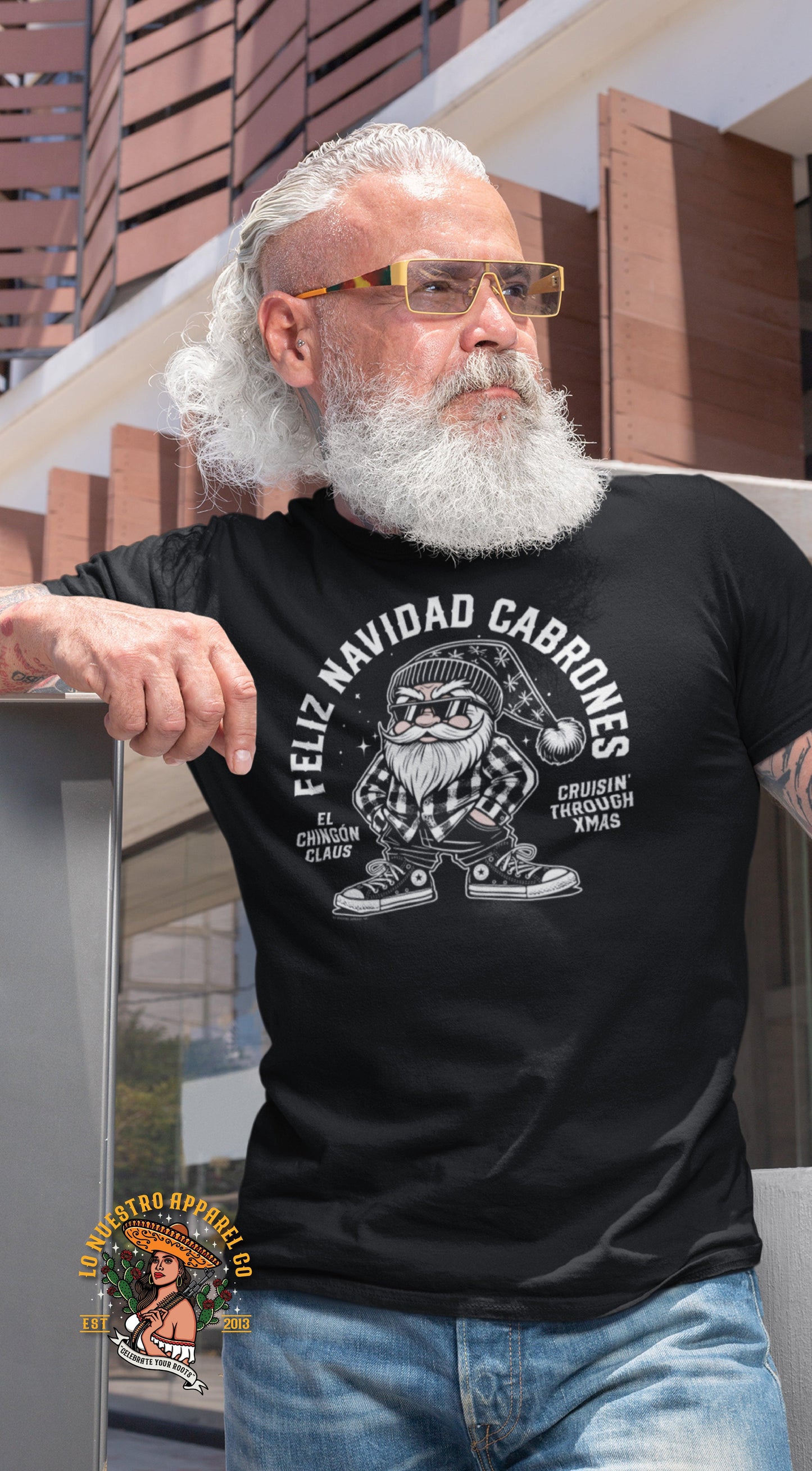 Man with white beard and glasses wearing a black 'Feliz Navidad Cabrones' t-shirt featuring El Chingón Claus and the words 'Cruisin’ through Xmas.' Styled with a cool and festive vibe.