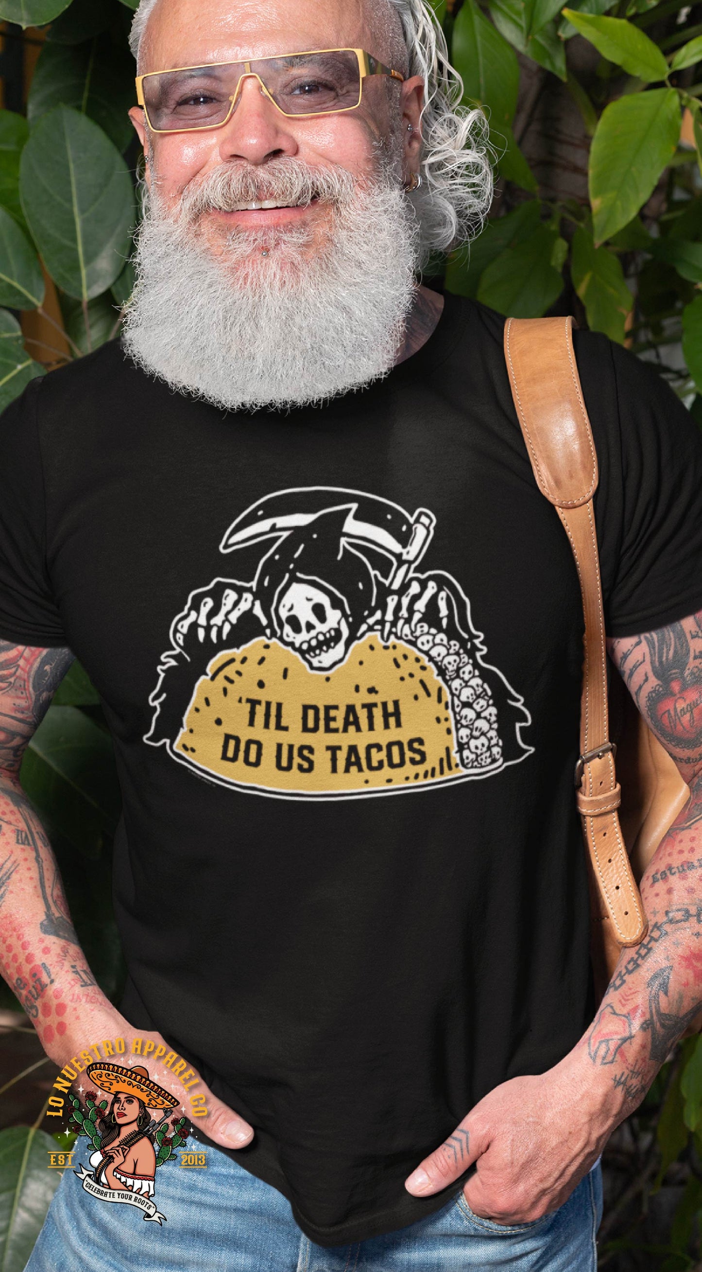 Man wearing 'Til Death Do Us Tacos' t-shirt with Grim Reaper holding a taco full of skulls design."