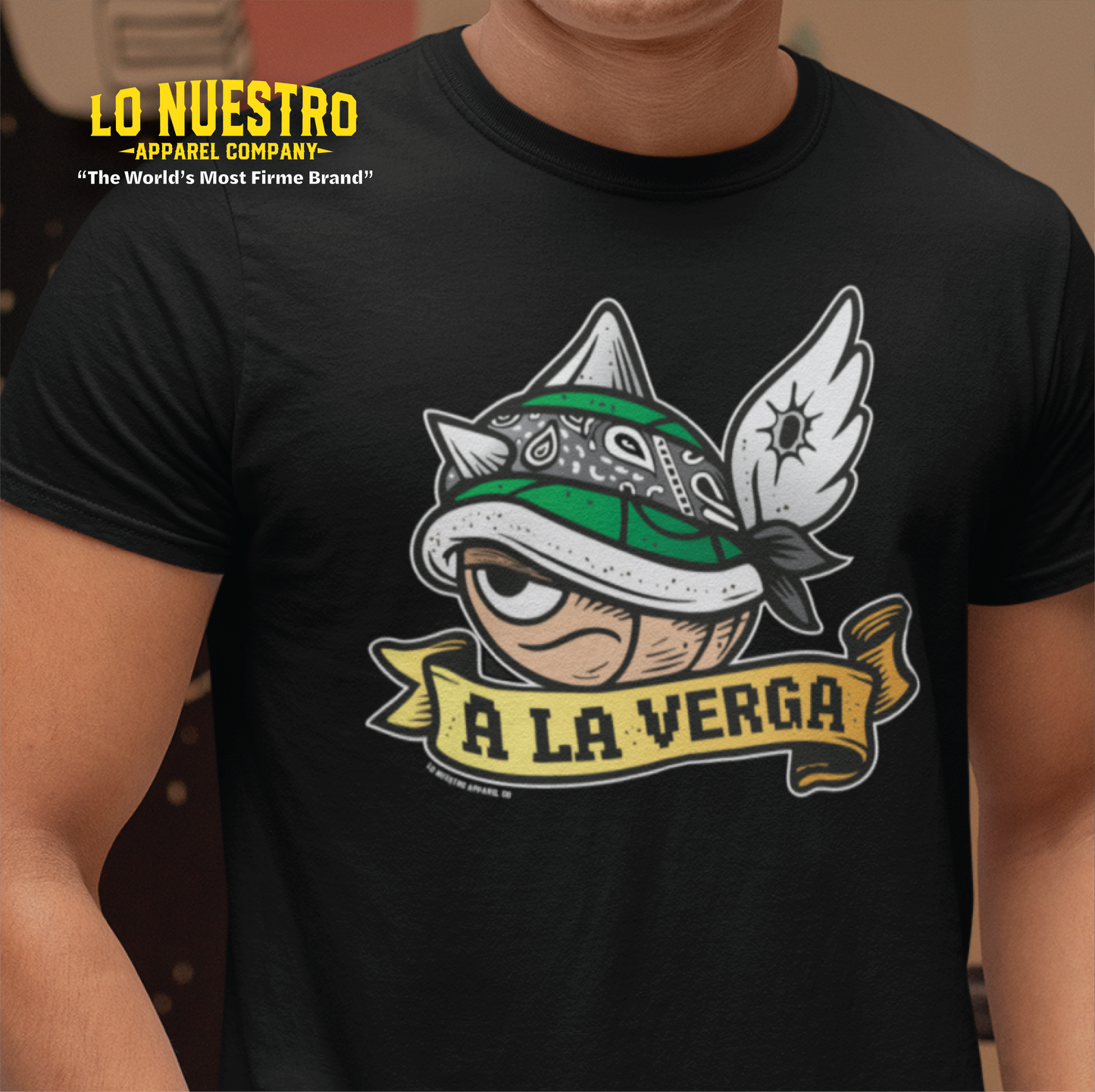 Model wearing A La Verga graphic t-shirt featuring a green shell with wings and street-style bandana; perfect for gamers and funny Mexican shirts.