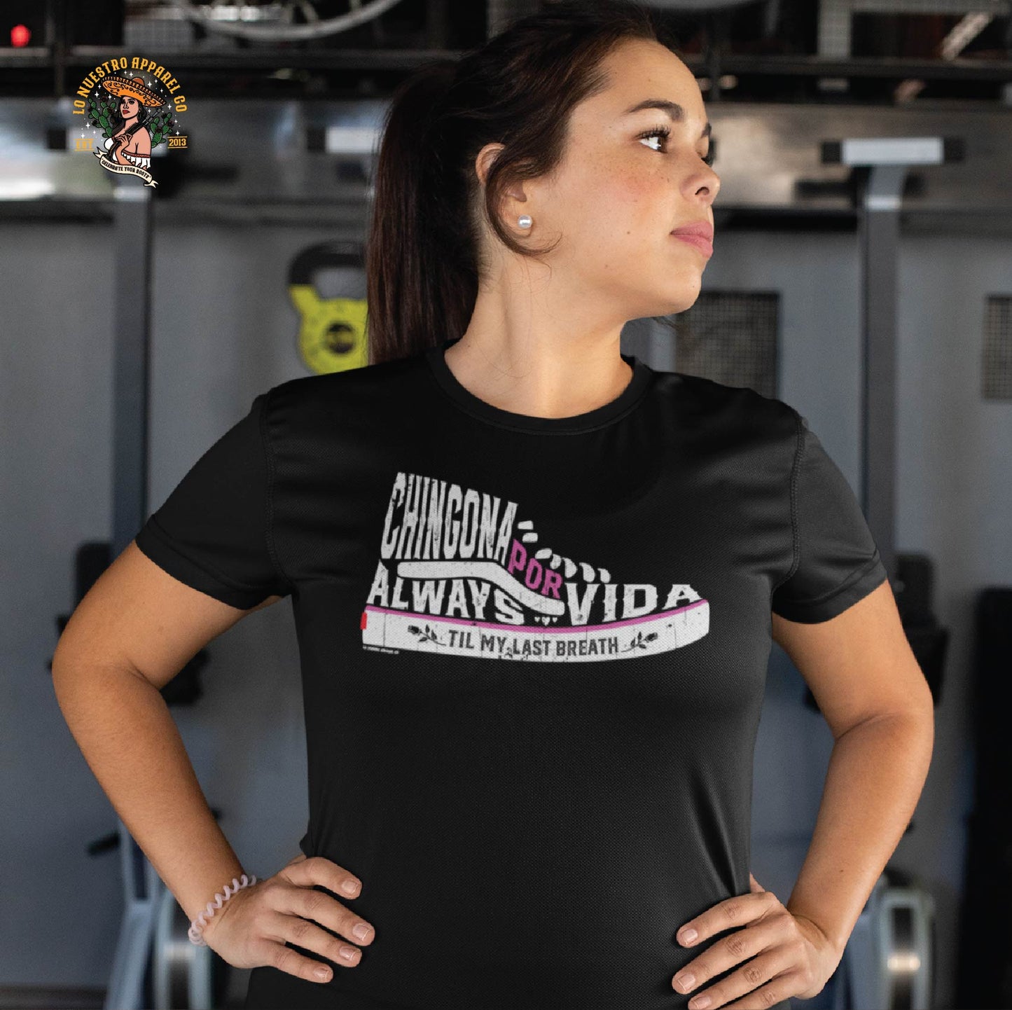 Chicana t-shirt mockup featuring a woman wearing the Chingona Por Vida shirt at the gym. A stylish and empowering Chicana shirt.