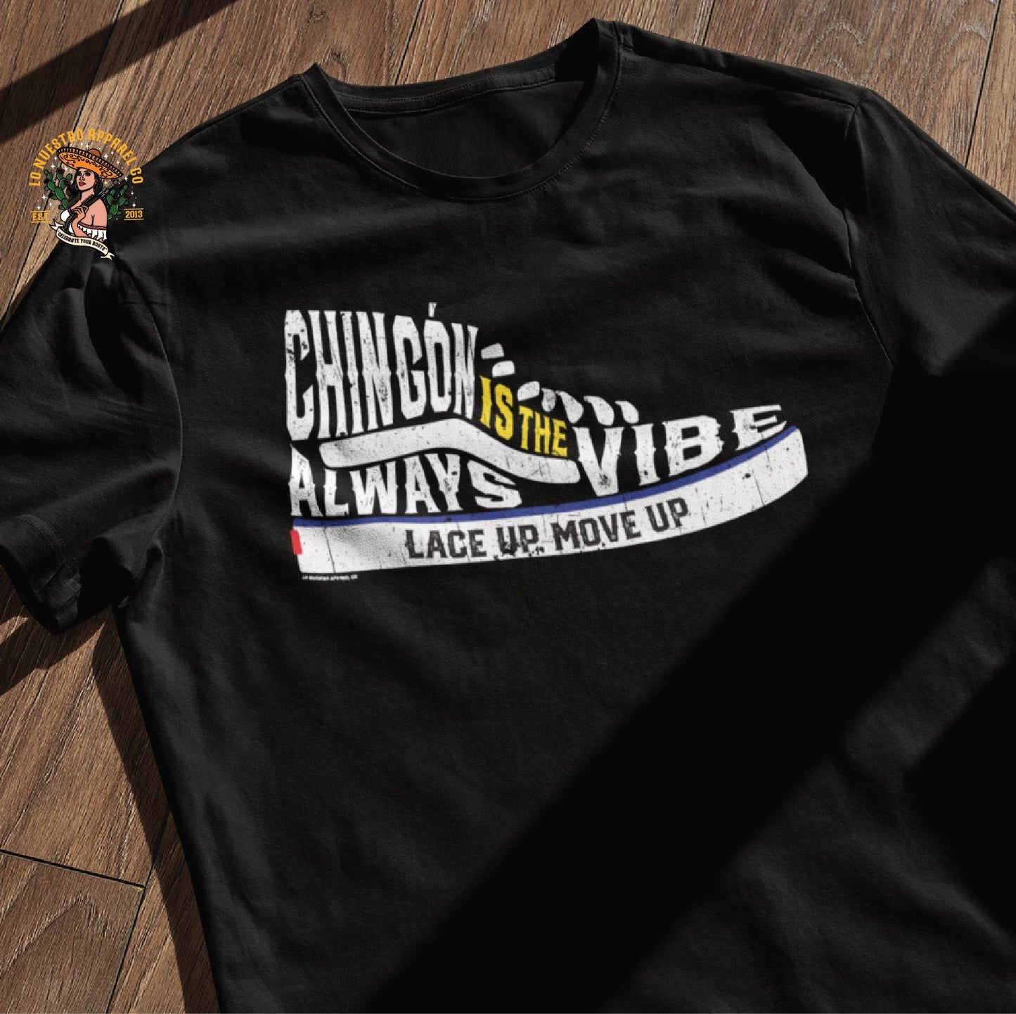 Black Chingón Is The Vibe shirt laid flat on a wooden surface, showcasing a sneaker-inspired design, perfect for fans of Mexican shirts and Chicano culture.