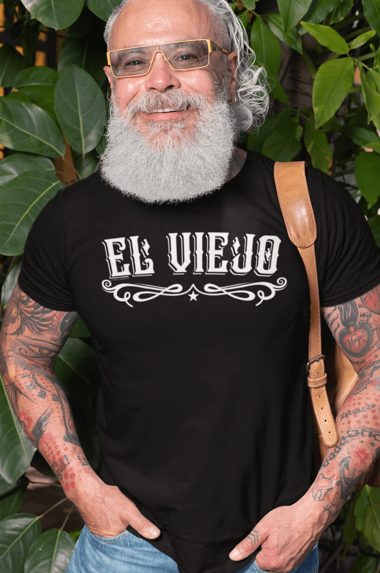 Tattooed man wearing the El Viejo Chicano T-Shirt, repping classic OG streetwear with bold typography and timeless design.
