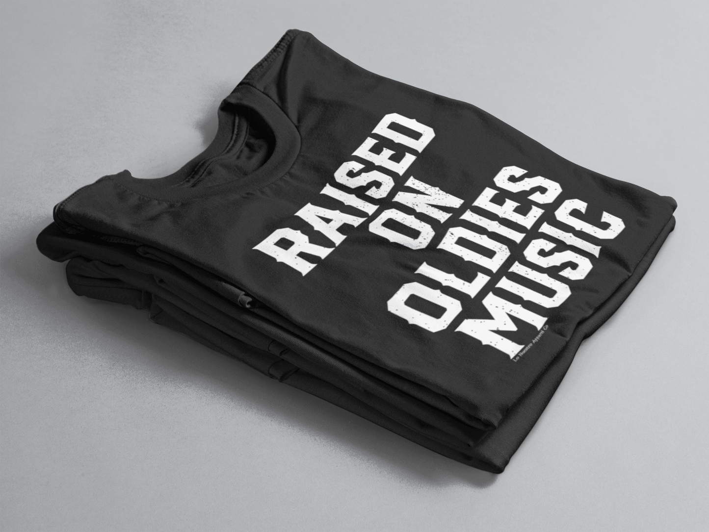 Close-up of a black women's t-shirt with the text 'Raised on Oldies Music,' highlighting the shirt's bold design and soft fabric.