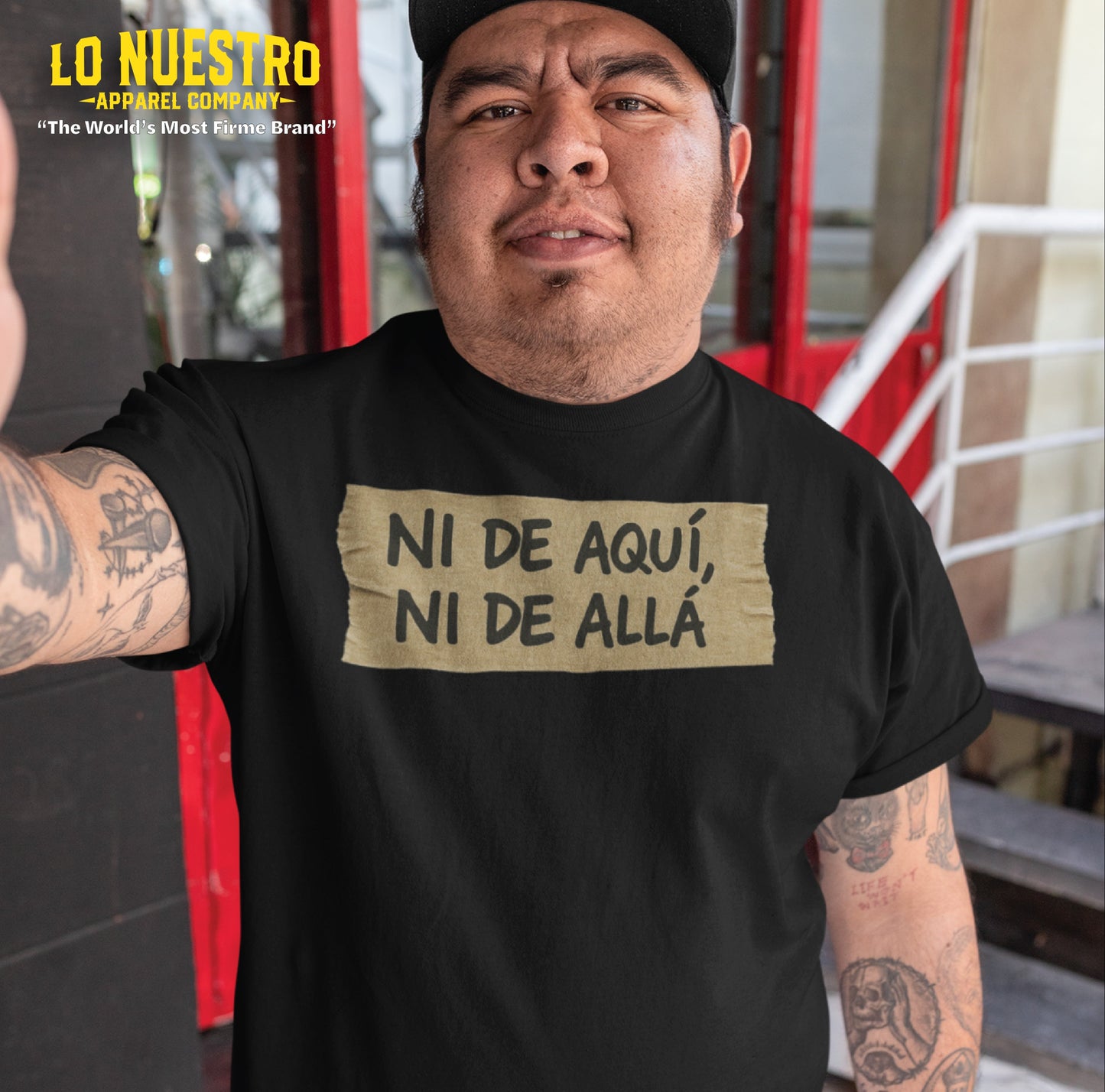 Mexican man wearing a funny Mexican shirt with masking tape design that reads Ni de aqui, ni de alla while taking a selfie