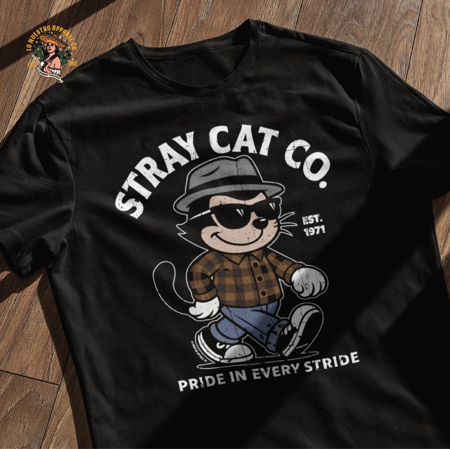 Flatlay of a funny shirt with a cartoon cat wearing a flannel, fedora, and sunglasses – Stray Cat Co. design with vintage Mexican vibes.