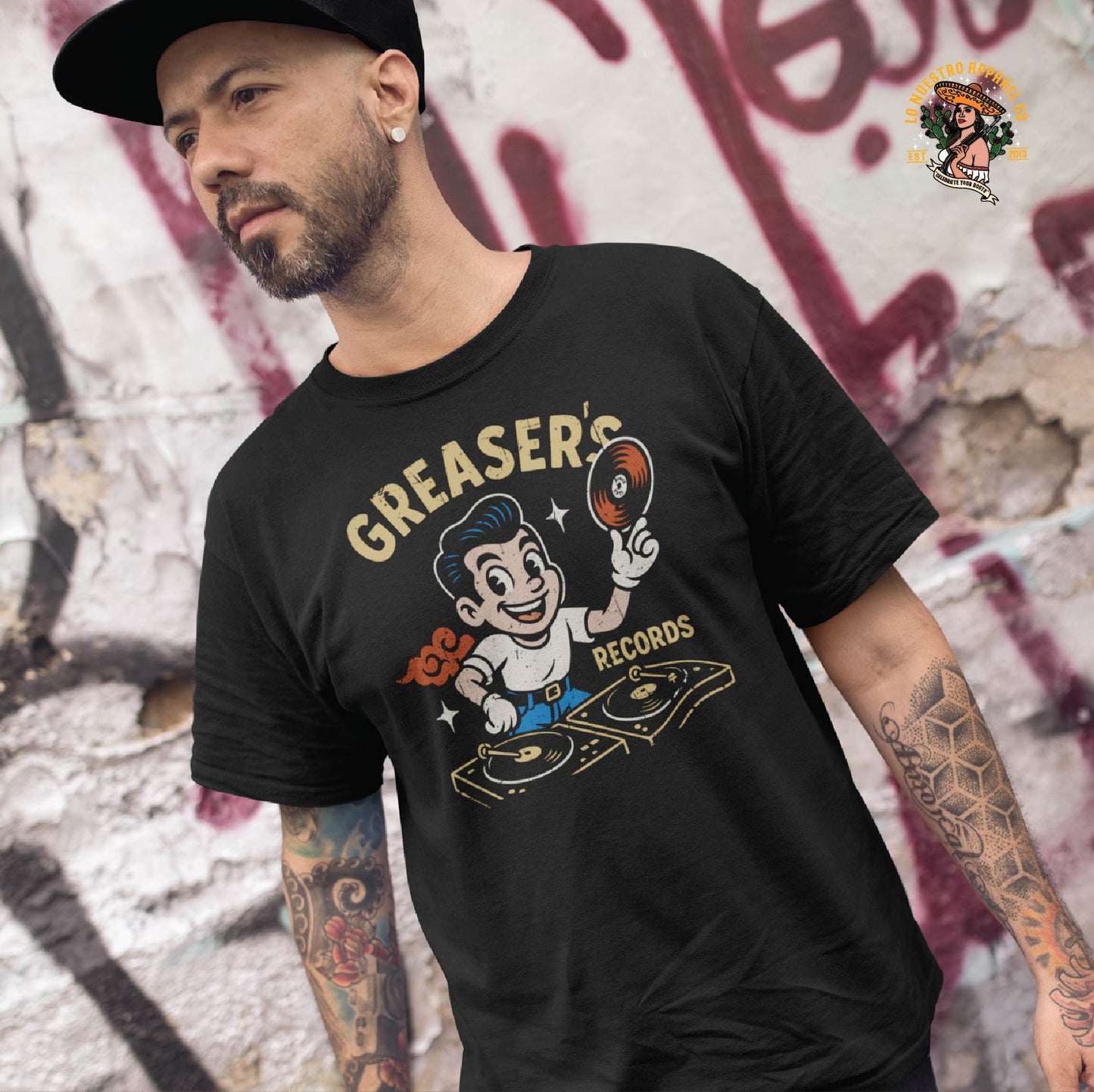 Tattooed man wearing the Greaser’s Records t-shirt in an urban setting. Funny Mexican shirt with vintage greaser cartoon for music lovers.