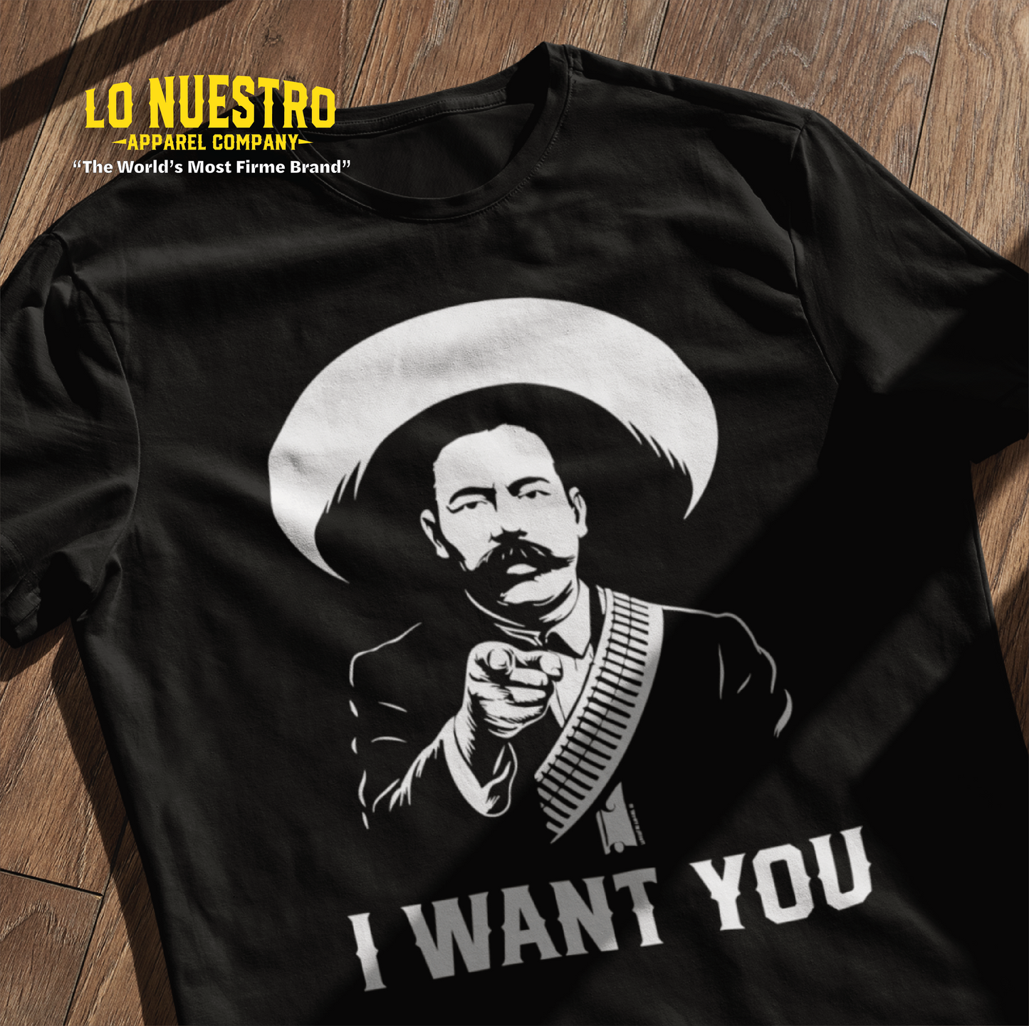Black t-shirt laying on a wooden floor with a graphic of a mustached revolutionary in a sombrero pointing forward, with the words I Want You below.