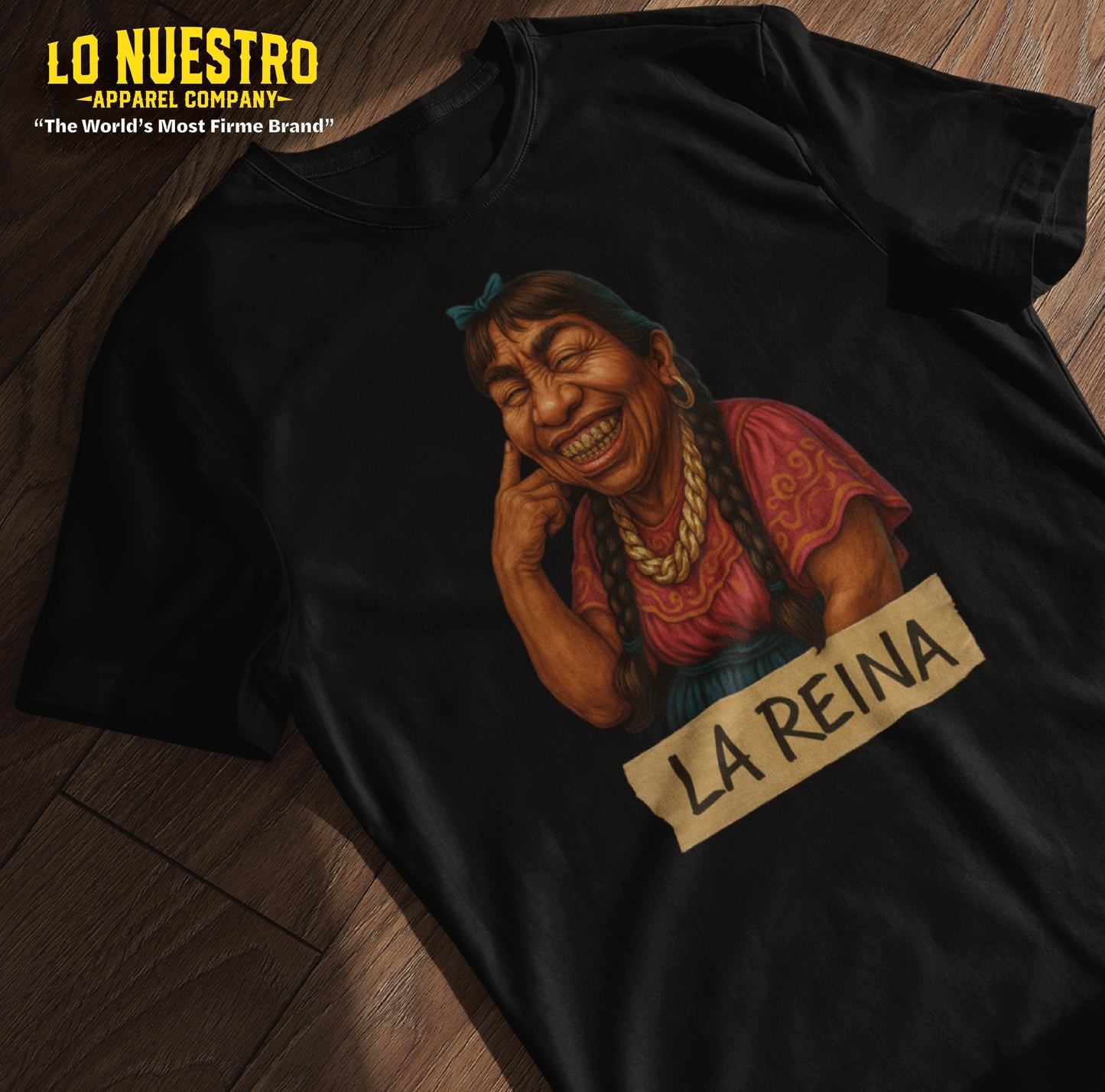 Flat lay of a funny Mexican shirt with a proud brown woman illustration and La Reina handwritten on masking tape – ideal for bold Latina vibes.