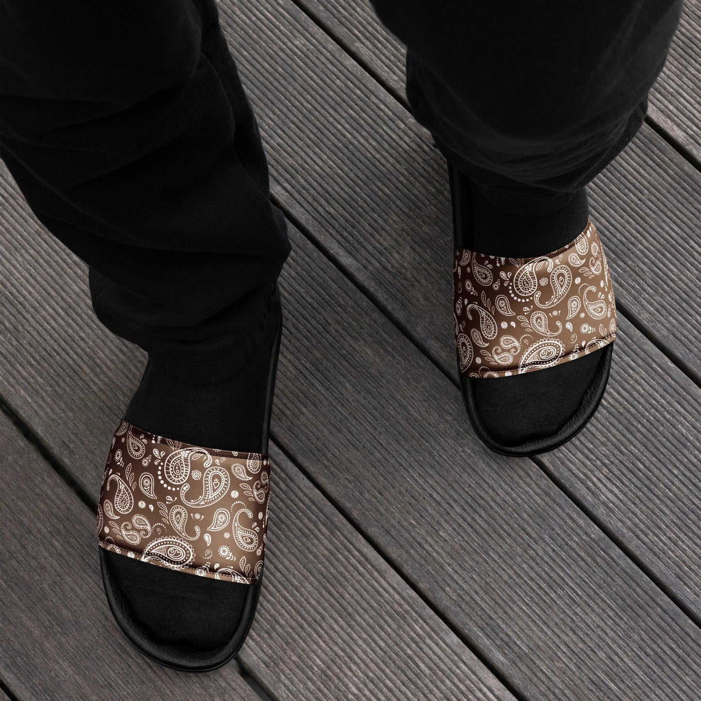 Person lounging on a wooden deck wearing Men's Brown Bandana Slide Sandals, adding a touch of street style to their casual look.