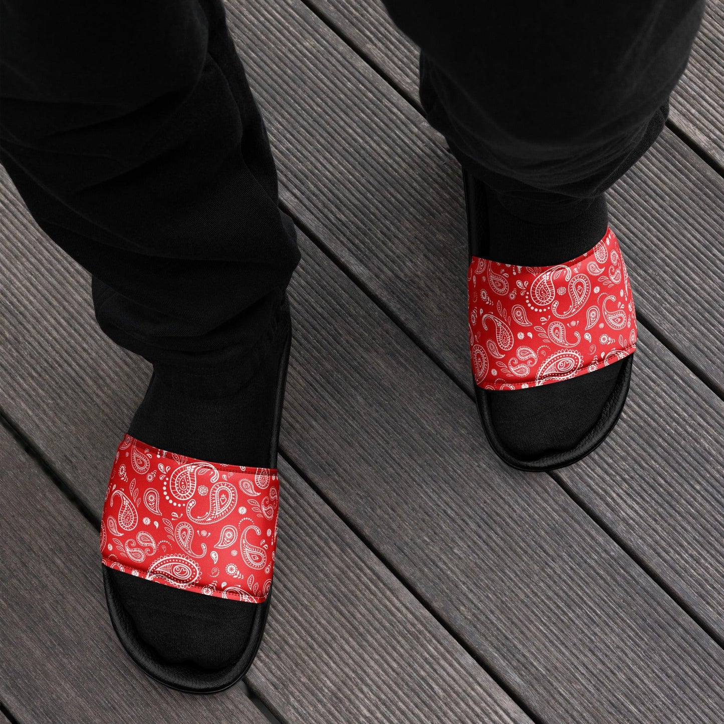 Person lounging on a wooden deck wearing Men's Red Bandana Slide Sandals, adding a touch of street style to their casual look.