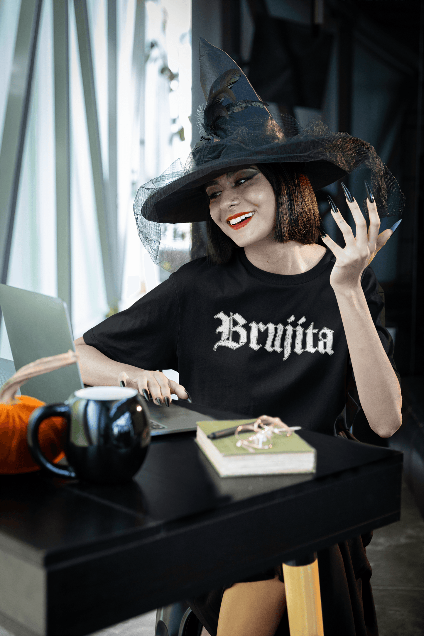Woman wearing Brujita T-Shirt and witch hat working from home – Stylish and comfortable witchy tee