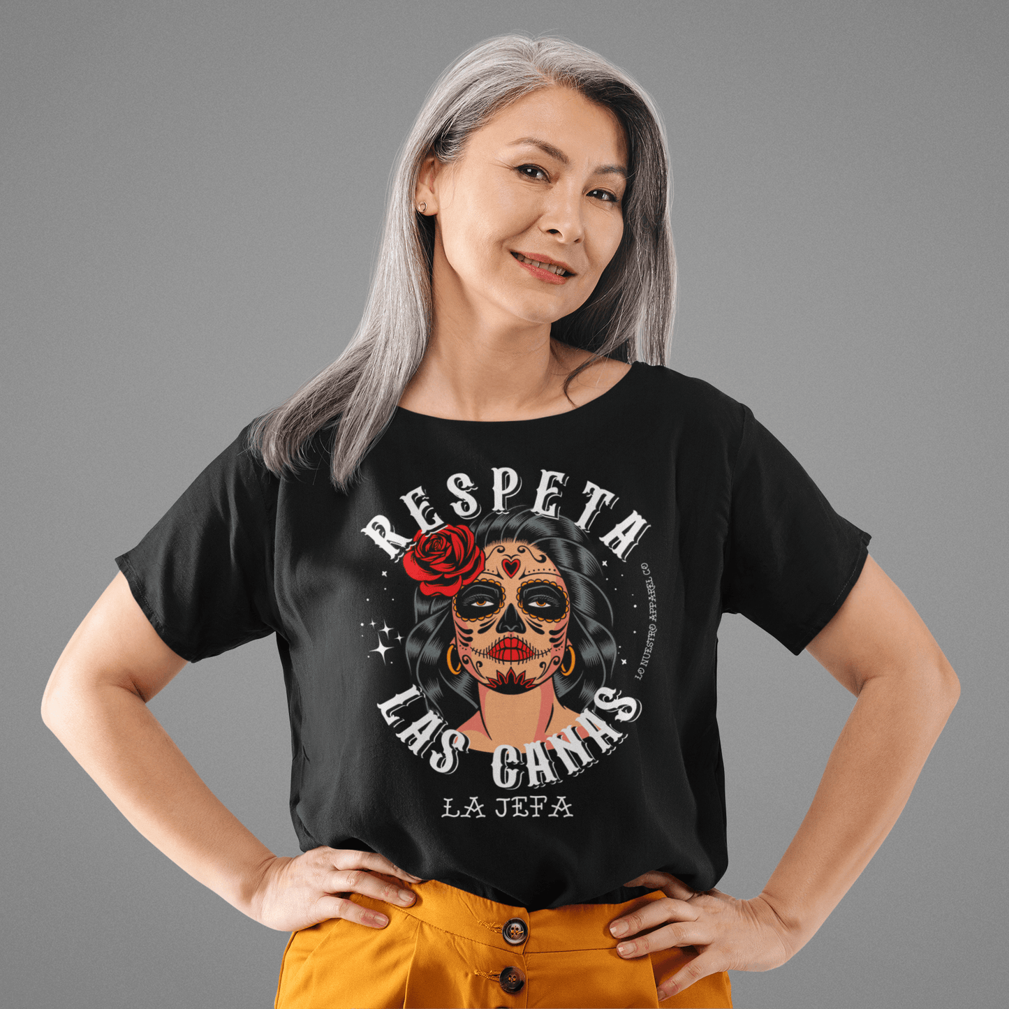 A woman confidently wearing the 'Respeta Las Canas' t-shirt in black, featuring a vibrant and empowering design.