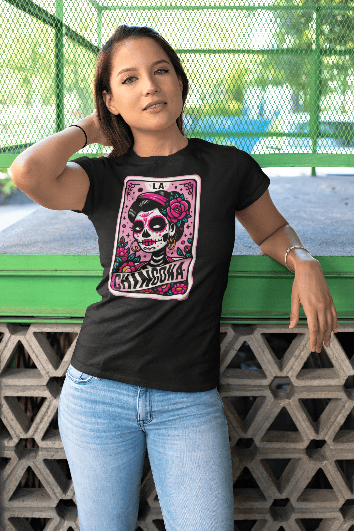 A woman confidently wearing the 'La Chingona' t-shirt in black, featuring a vibrant and empowering tarot card design.