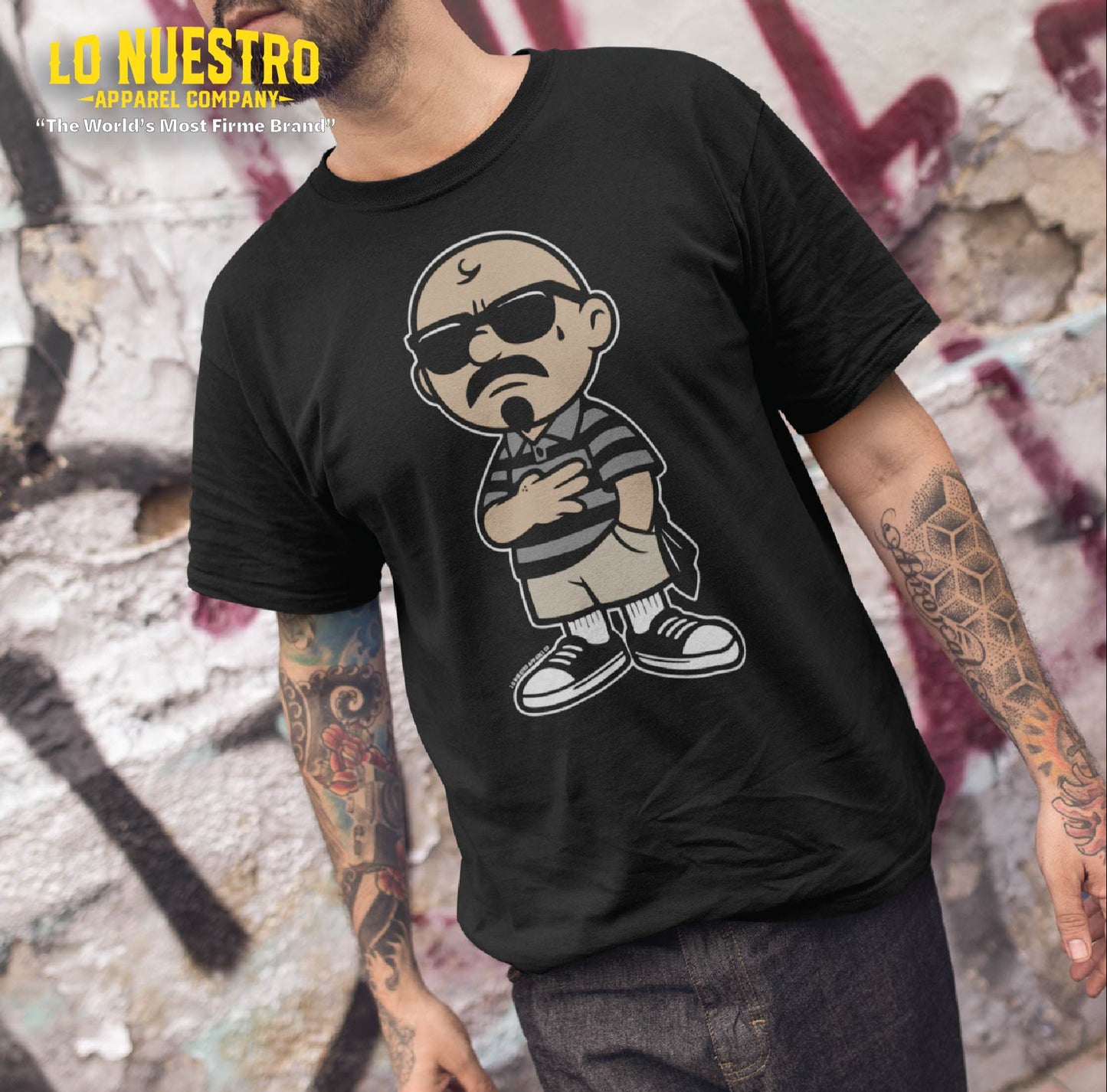 Tattooed man wearing a funny Mexican shirt with cartoon homie artwork. Chicano clothing streetwear mockup in an urban setting.