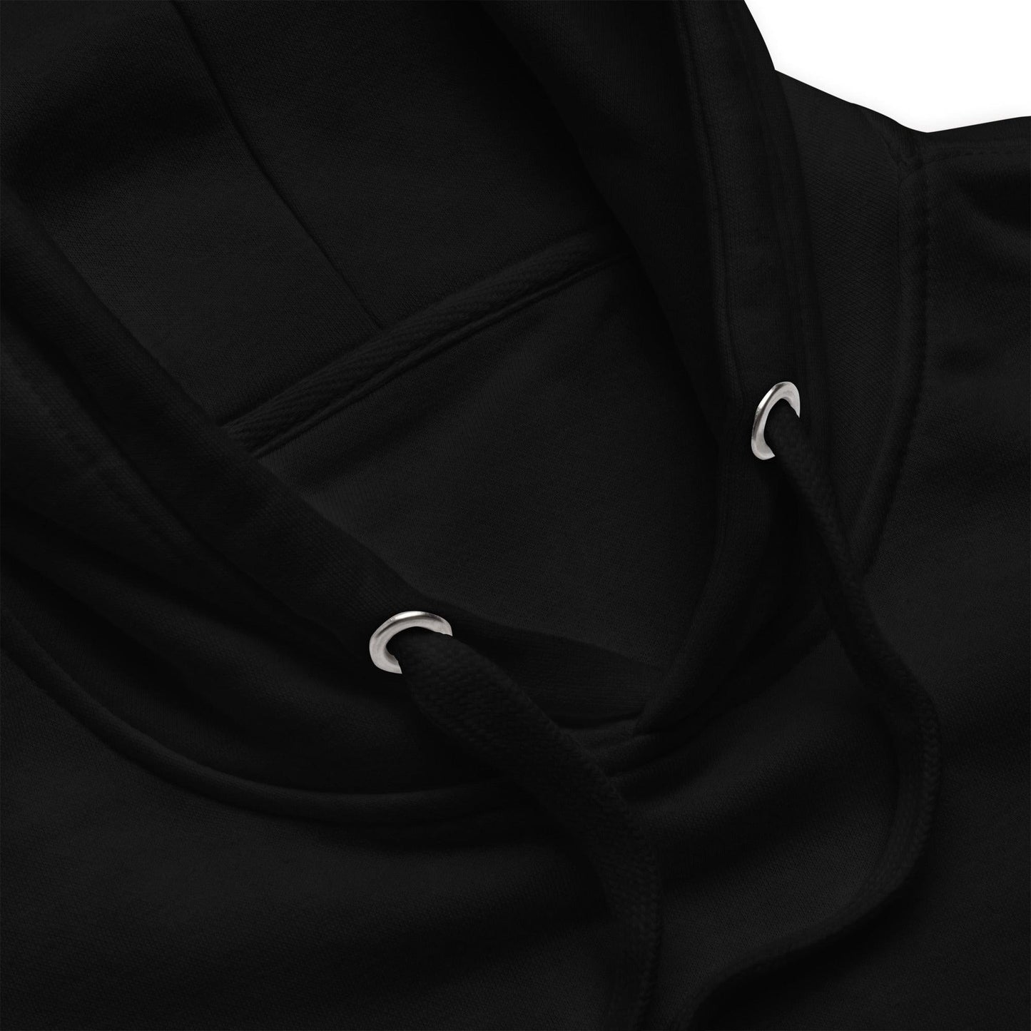 Close-up detail of a black hoodie showing the drawstrings and the reinforced eyelets on the hood, highlighting the fabric texture and stitching.