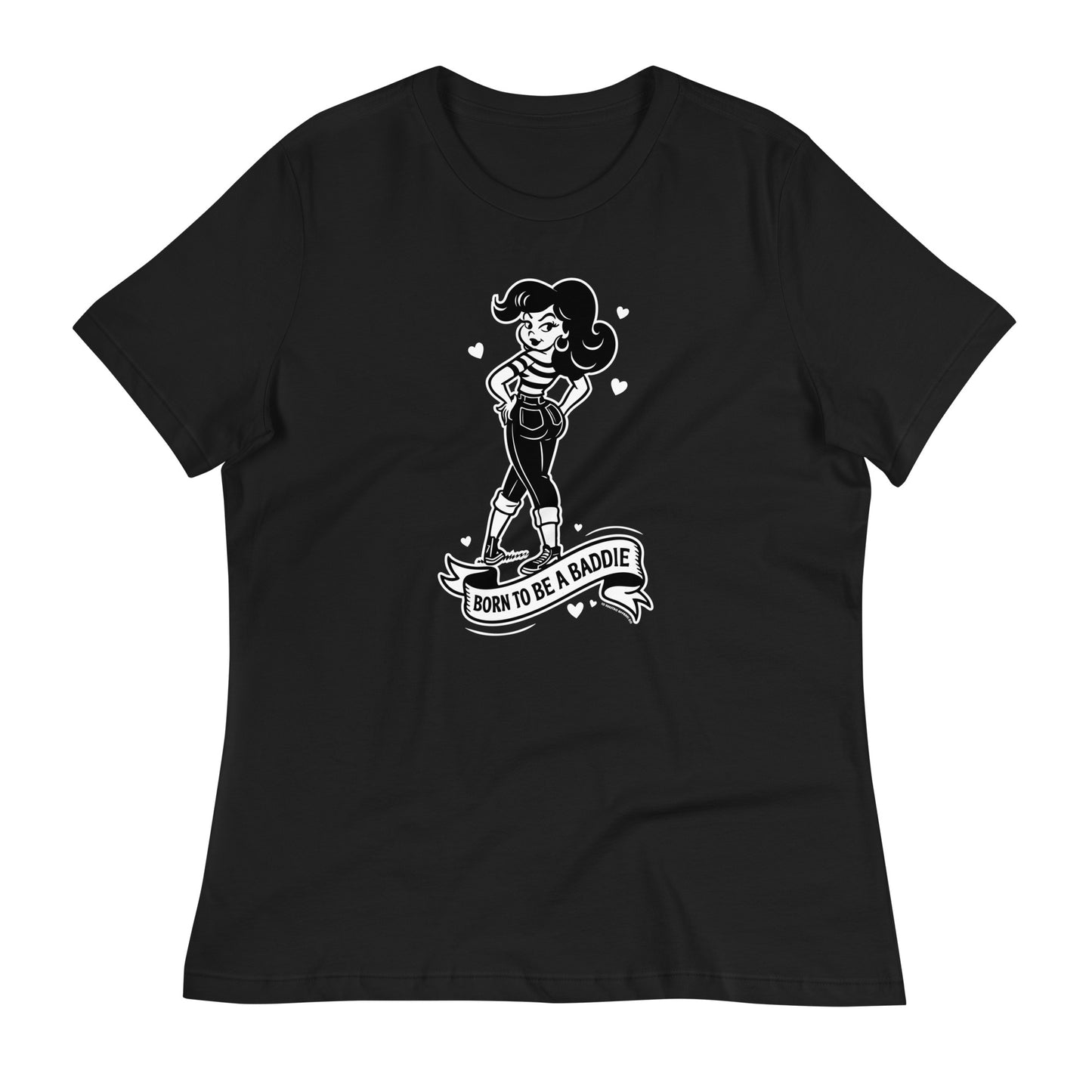 Flatlay of a black Chicana shirt on a wooden floor featuring a vintage cartoon-style girl with the phrase Born to Be a Baddie.