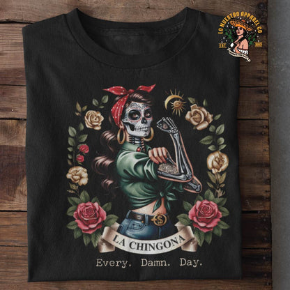 La Chingona, Every Damn Day, folded on a wooden table showcasing Lo Nuestro Apparel's funny shirts and Chicano Clothing line.