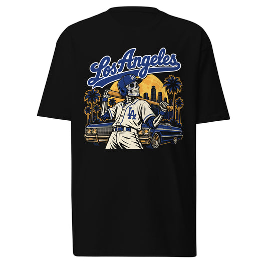 lack Los Angeles baseball graphic t-shirt featuring a Día de los Muertos skeleton batter wearing a blue baseball uniform, a classic blue lowrider, palm trees, downtown LA skyline, and golden full moon beneath bold Los Angeles lettering.