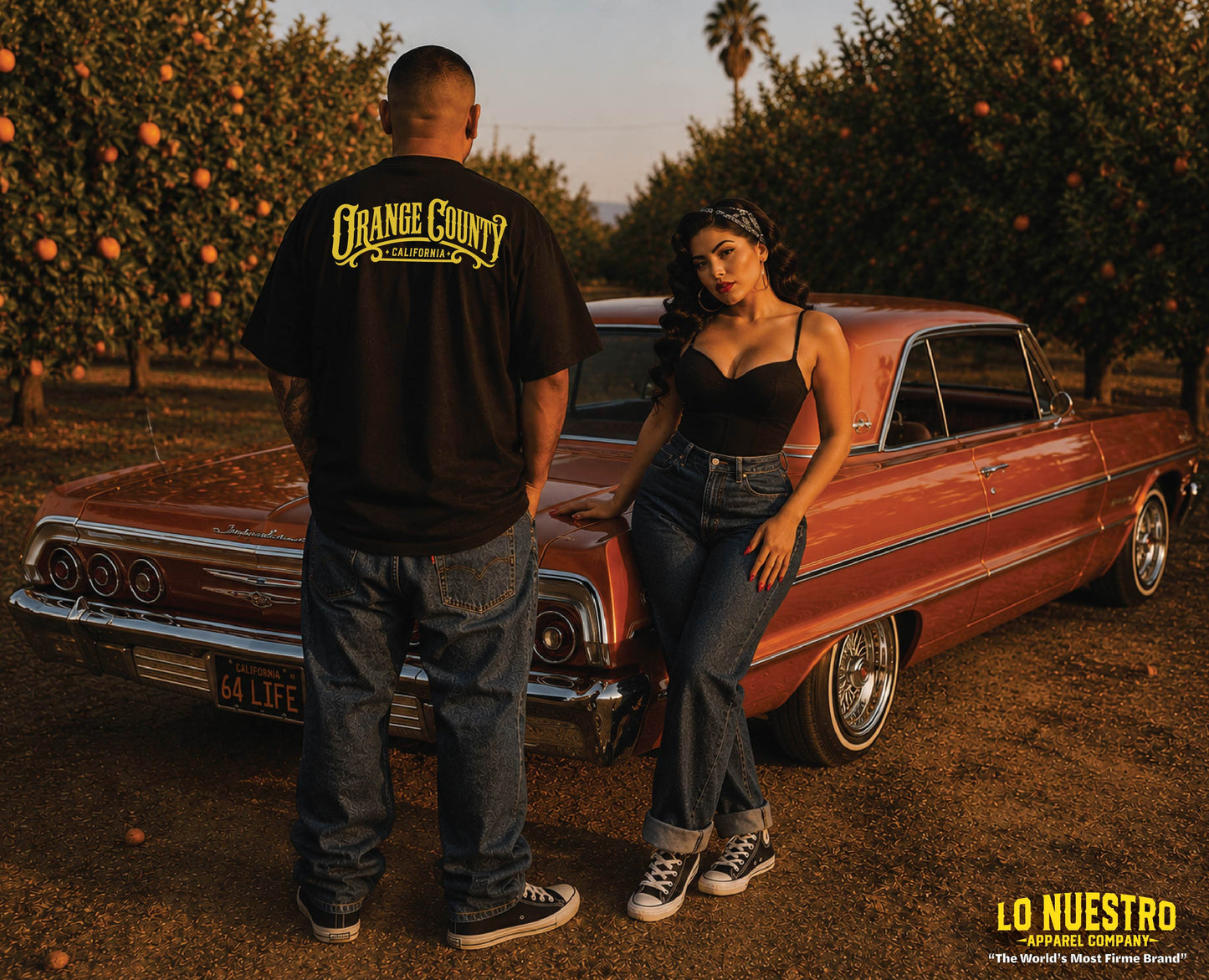 Back view of the Orange County Plaque t-shirt worn in an orange grove showing the large back graphic in front of a candy orange 1964 Impala lowrider.
