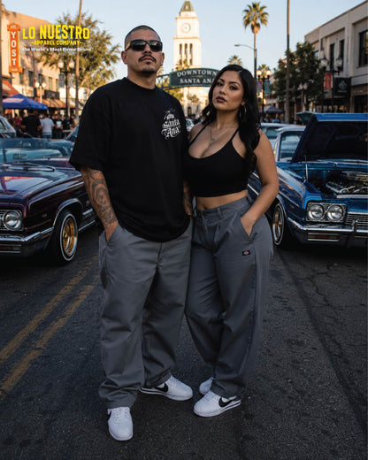 Front view of man wearing black Santa Ana Old English T-shirt with woman standing beside him in downtown Santa Ana.