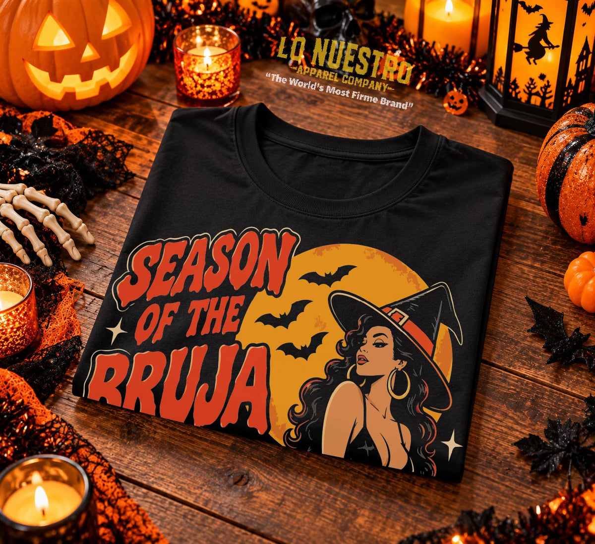 Folded black Season of the Bruja t-shirt displayed with pumpkins, candles and Halloween decorations