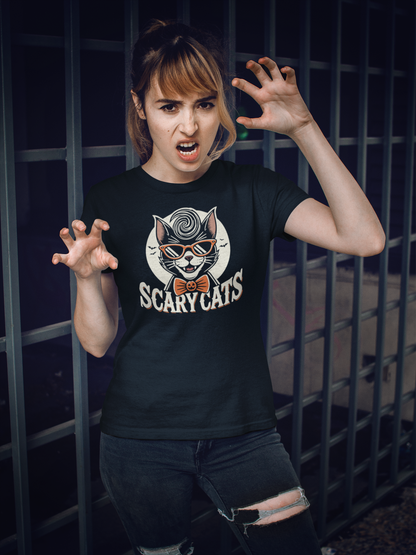 Woman posing fiercely in a black t-shirt with a 'Scary Cats' design, featuring a cool retro cat with sunglasses and a jack-o-lantern bow tie, against a barred fence background.