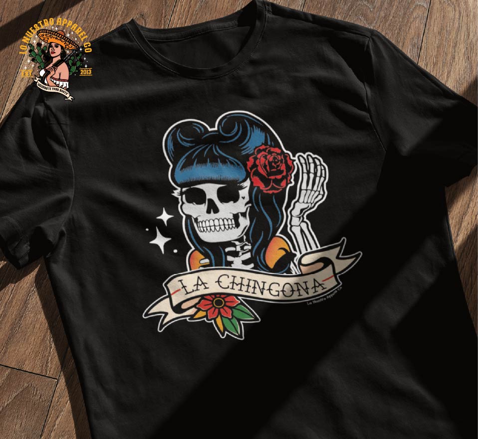 The La Chingona Tattoo Style Pin Up T-shirt on a wooden floor. Funny Mexican T Shirts and Chicano Clothing is what Lo Nuestro Apparel Co specializes in.