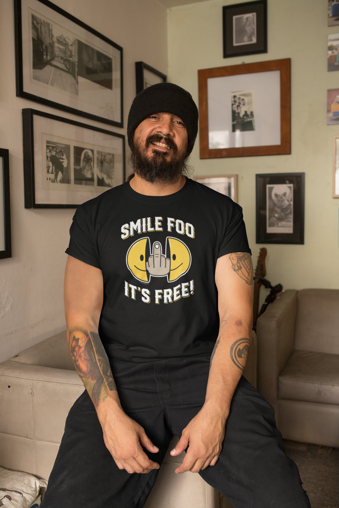 Mockup of a man wearing the Smile Foo It's Free Funny T-Shirt, pointing at the graphic while standing in a rustic bar setting.