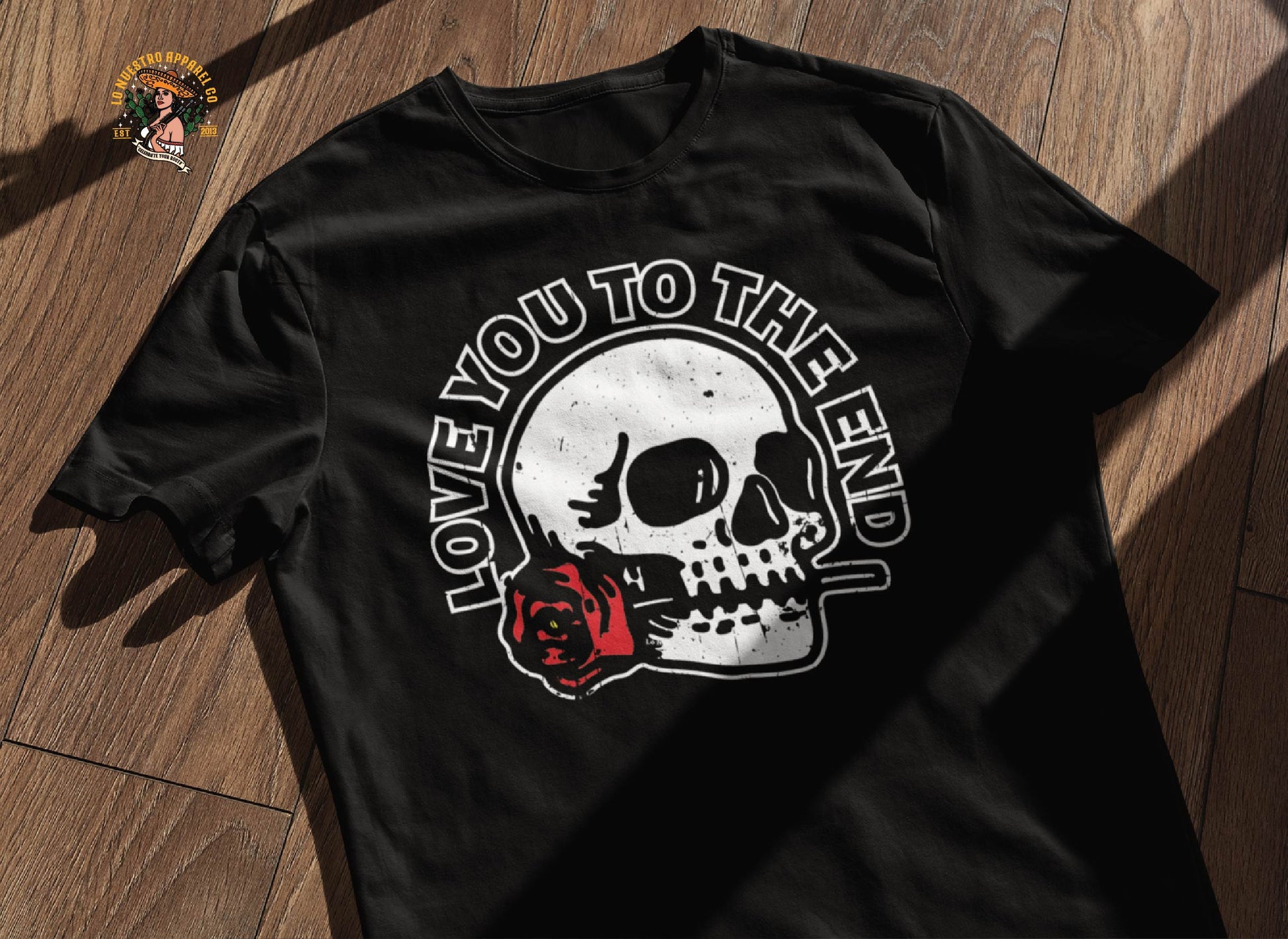 Our Skull and Roses Shirt featuring a distressed look on a wooden floor. Our Skull Shirt and all other skull T-shirt in our Chicano Clothing fall under the funny Mexican Shirts section.