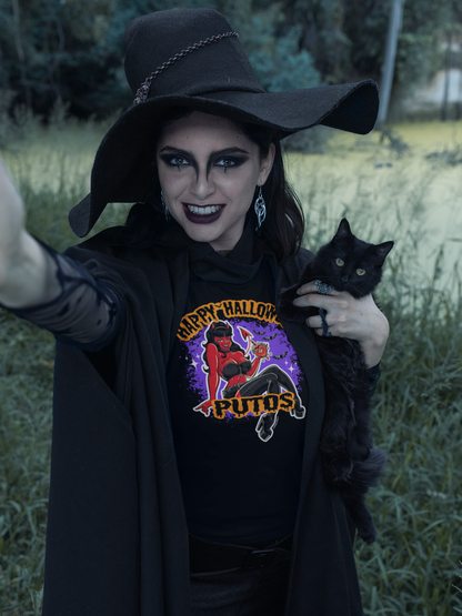 A witchy woman in a black hat holding a black cat, wearing a "Happy Halloween Putos" T-shirt with a devil girl graphic, smiling mischievously.