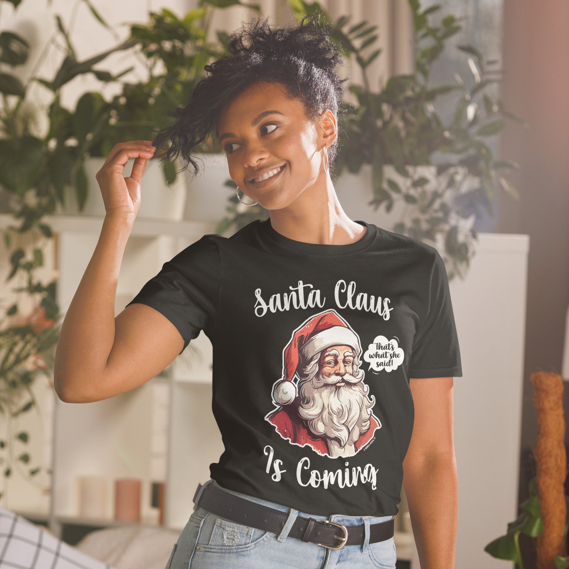 Woman smiling and wearing a "Santa Claus Is Coming" unisex shirt, bringing out the funny and festive spirit.