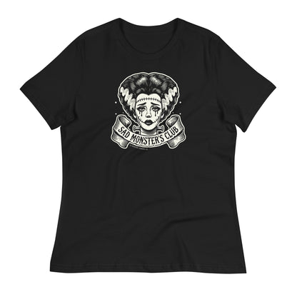 Black women's t-shirt featuring a retro tattoo-style design of the Bride of Frankenstein with the text 'Sad Monster's Club' in a banner below. The shirt is laid flat on a white background.