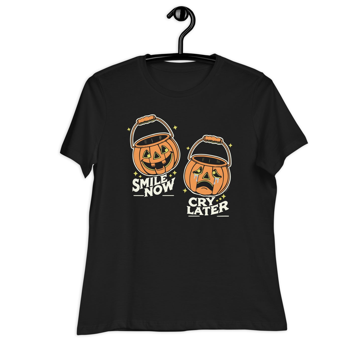 A women's relaxed fit t-shirt in black  on a hanger featuring the 'Smile Now, Cry Later' jack-o'-lantern design. The retro Halloween style shows two pumpkin buckets, one smiling and one crying.