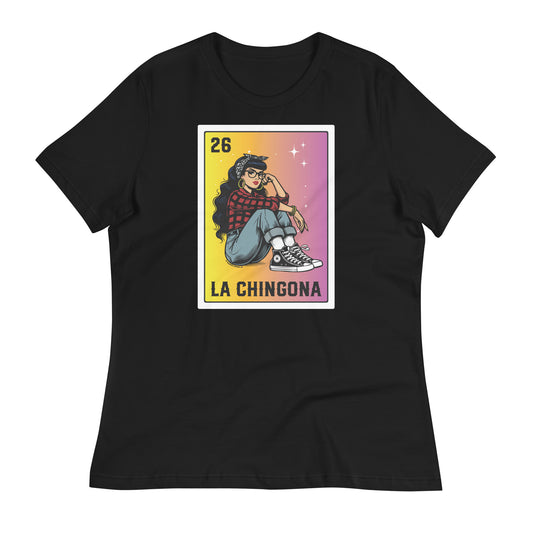 A close-up of a black t-shirt with a vibrant "La Chingona" Loteria-style design featuring a Chicana sitting cross-legged in a red plaid shirt, jeans, and Converse sneakers, against a gradient yellow to pink background.