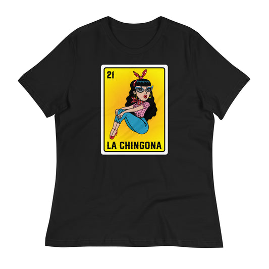 A close-up of a black t-shirt with a vibrant "La Chingona" Loteria-style design featuring a Chicana sitting  in a pink plaid shirt, jeans, and high heels, against a gradient orange to yellow background.